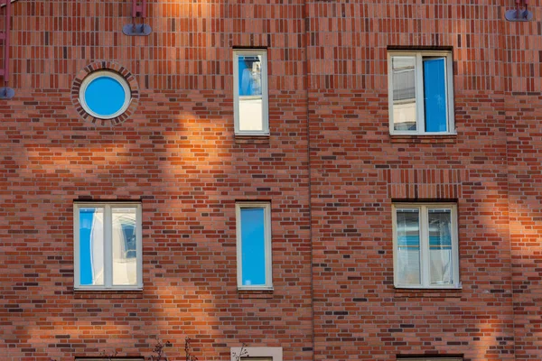 Brick wall with five square windows and one round.