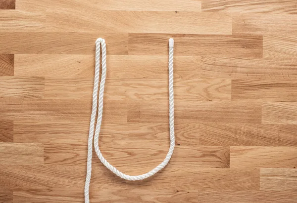 字母U是用白色的绳子在木制桌子上形成的 — 图库照片