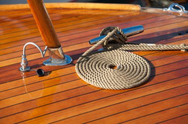 Bir teknenin ahşap güvertesine düzgün bir şekilde sarılmış ip..