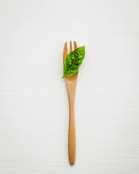 Closeup  fresh sweet basil leaves with fork  on white wooden bac — Stock Photo, Image