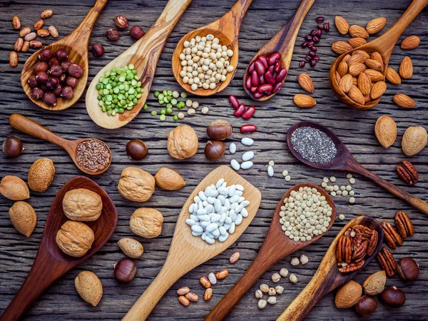 Various legumes and different kinds of nutshells in spoons. Waln — Stock Photo, Image