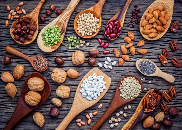 Various legumes and different kinds of nutshells in spoons. Waln — Stock Photo, Image