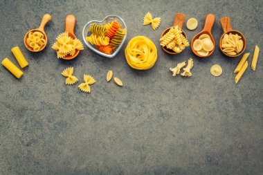 İtalyan gıda kavramı ve menü tasarımı. Makarna Farfalle, makarna A Riso, Orecchiette Pugliesi, Gnocco Sardo ve Farfalle çeşitli tür düz lay ile taş zemin üzerine tahta kaşıklar kurulumunda.