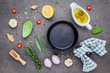 Karanlık taş zemin üzerinde boş eski dökme demir becerisi. Fotokopi alanı ile biftek konsepti yapmak için gerekli malzemeler. Çeşitli otlar ve baharat biberiyesi, adaçayı, defne yaprağı, fesleğen, sarımsak ve biber..