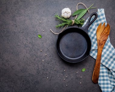 Karanlık taş zemin üzerinde boş eski dökme demir becerisi. Fotokopi alanı ile biftek konsepti yapmak için gerekli malzemeler. Çeşitli otlar ve baharat biberiyesi, adaçayı, defne yaprağı, fesleğen, sarımsak ve biber..