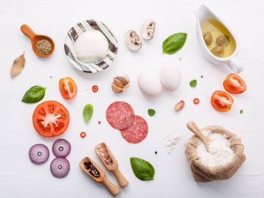 Malzemeler fesleğen, domates, sarımsak, defne yaprağı, biber, soğan ve mozzarella peyniri düz lay ile beyaz ahşap zemin üzerinde ev yapımı pizza için malzemeler.