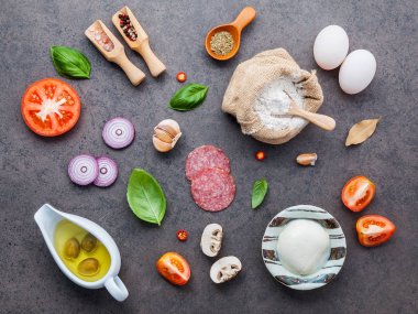 Malzemeler Reyhan, domates, sarımsak, defne yaprağı, biber, soğan ve mozzarella peyniri düz lay ile karanlık taş zemin üzerine ev yapımı pizza için malzemeler.
