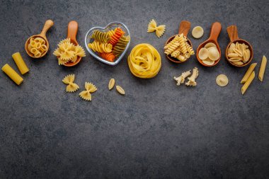 İtalyan gıda kavramı ve menü tasarımı. Makarna Farfalle, makarna A Riso, Orecchiette Pugliesi, Gnocco Sardo ve Farfalle çeşitli tür düz lay ile taş zemin üzerine tahta kaşıklar kurulumunda.