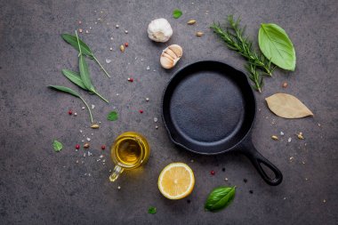 Karanlık taş zemin üzerinde boş eski dökme demir becerisi. Fotokopi alanı ile biftek konsepti yapmak için gerekli malzemeler. Çeşitli otlar ve baharat biberiyesi, adaçayı, defne yaprağı, fesleğen, sarımsak ve biber..
