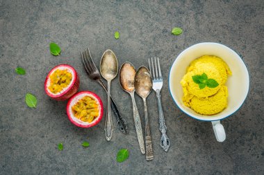 Vintage kase kurulum karanlık taş zemin üzerine dondurma tutku meyve tadında bileşimi. Biber nane yaprakları ve gereçler ile tutku meyve.