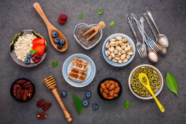 Sağlıklı gıdalar için malzemeler karışık Kuruyemiş, tatlım, meyveler, meyve, yaban mersini, portakal, badem, yulaf ezmesi ve chia tohum arka plan. Sağlıklı gıda kavramı koyu taş arka plan üzerinde kurmak.