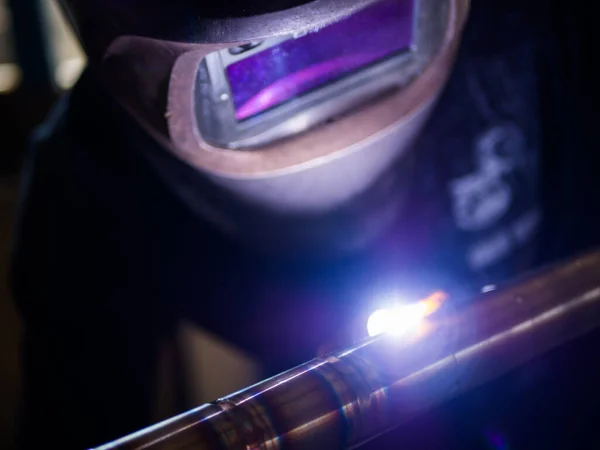 İşçi, TIG meşalesi kullanarak paslanmaz boruları kaynak yapıyor. Tungsten Durağan Gaz Kaynağı.
