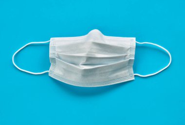Açık mavi arkaplanda cerrahi maske izole edilmiş.