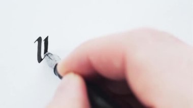 El yazısıyla yazılmış kelimeler. Erkek eller kalemle yazar. Kaligrafi yakın plan.