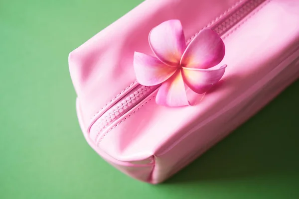 Pink cosmetic bag on green.