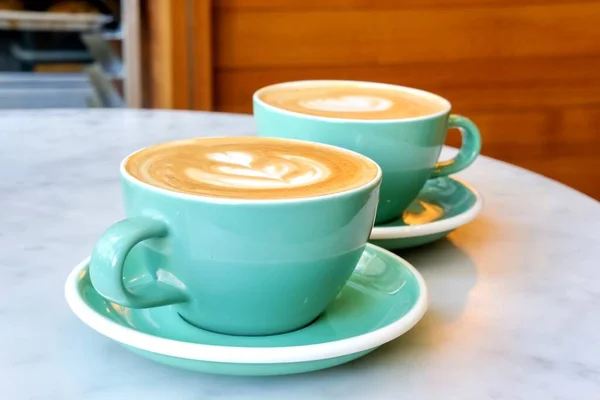 Two cups of coffee in mint green mugs.