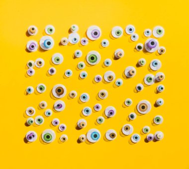 Parlak sarı arka planda farklı boyutlarda renkli plastik gözler. Komik moda konsepti. 