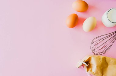 Pişirme malzemeleri, un, süt ve yumurta pembe arka planda. Gıda düzlüğü minimum konsept içerir.