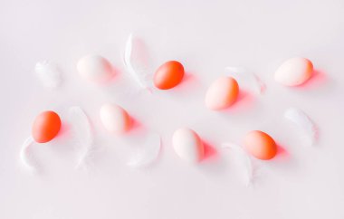 Pastel gri arka planda beyaz ve kırmızı yumurtalar ve tüyler. Paskalya konsepti.