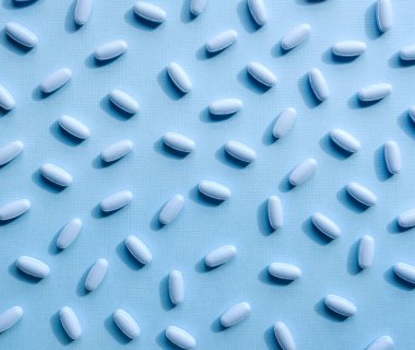 Pastel arka planda mavi ilaç hapları ve kapsüller.