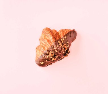 Pastel pembe arka planda klasik ve koyu çikolatalı kruvasan. Tatlı yemek tasarımı. 