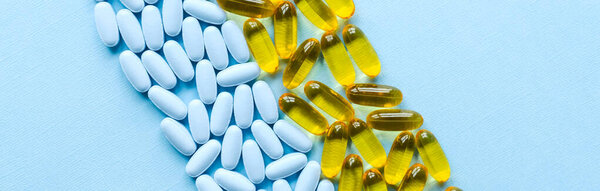 Colorful medicine pills and capsules on blue background banner.