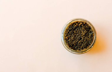 Cam kasede siyah havyar. Yüksek kaliteli gerçek mersin balığı kara havyar, pastel arka planda lüks şarküteri.. 