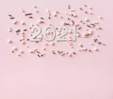 Gümüş Noel süslemeleri ve pastel pembe arka planda şeker parçacıkları. Düz yatış stili. Klasik tatil konsepti.