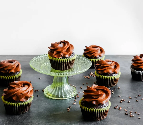 Dark chocolate cupcakes and cocoa nibs on dark background. Sweet food concept.