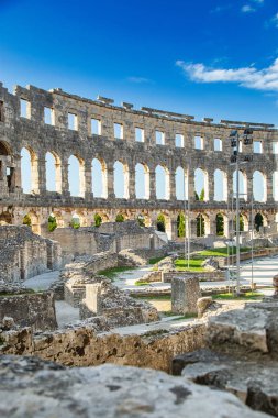 Hırvatistan 'ın Pula kentindeki antik miras. Antik Roma arenasının kemerleri. Tarihi amfi tiyatronun içi, mavi arka plandaki yüksek duvarların geniş açılı görüntüsü..