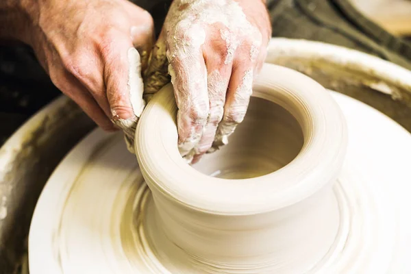 Potter making clay bowl or vase ceramics on the potter's wheel. Creating pottery art and handicraft modelling creation. Hands detail.