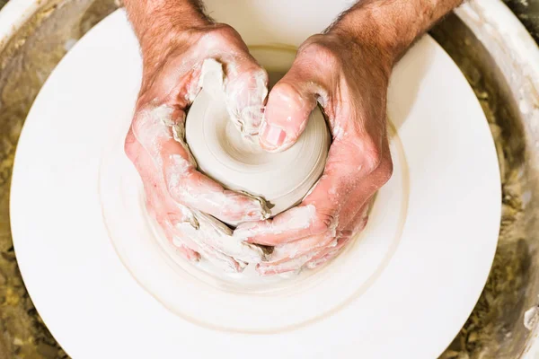 Potter making clay bowl or vase ceramics on the potter's wheel. Creating pottery art and handicraft modelling creation. Hands detail.
