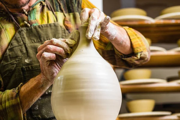 Potter working on potter's wheel, making new bowl from raw clay, hands detail