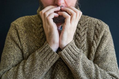 Depresyondaki mutsuz, kafası çapraz kollarda, yarım suratlı, endişeli bir adam.