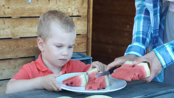 Menino come uma melancia de um prato branco — Fotografia de Stock