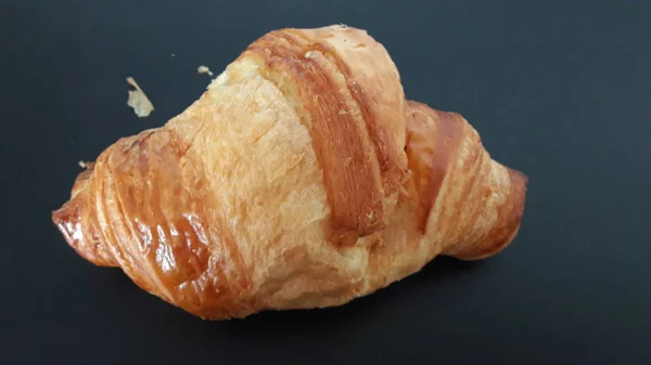 Croissant em um fundo preto — Fotografia de Stock