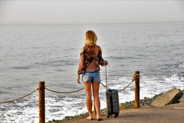 Ragazza Leva Piedi Sull Oceano Con Una Valigia Guarda Avanti — Foto Stock