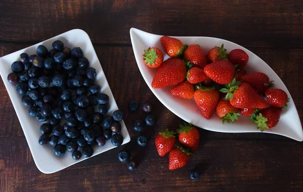 新鲜成熟的草莓和蓝莓 白盘放在木制桌子上 — 图库照片