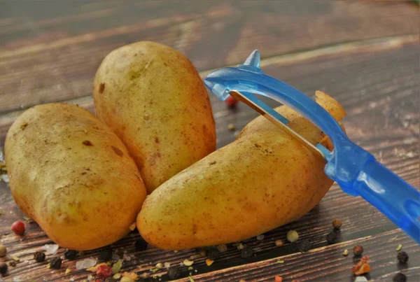 Jonge Aardappelen Een Aardappelschiller Een Houten Tafel — Stockfoto