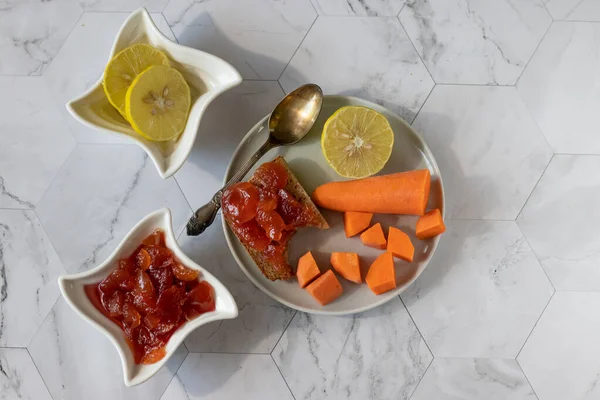 Homemade carrot jam with lemon, sugar and vanilla. In a saucer on a light background — 图库照片