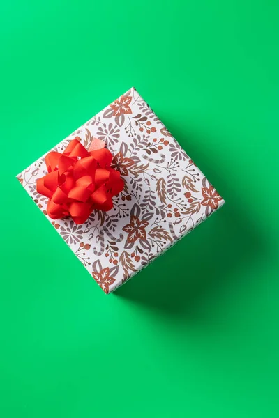 Caixa de presente com um arco vermelho em um fundo verde, para o feriado. Espaço de cópia — Fotografia de Stock