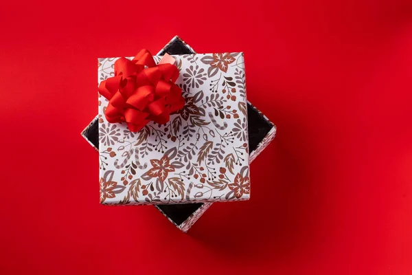 Gift box with a red bow on a red background for the holiday. Copy space — Stock Photo, Image