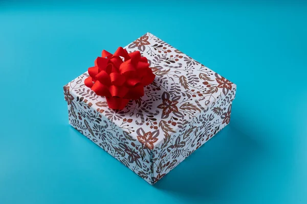 Κουτί δώρου με κόκκινο φιόγκο σε μπλε φόντο για τις διακοπές. Αντιγραφή χώρου — Φωτογραφία Αρχείου