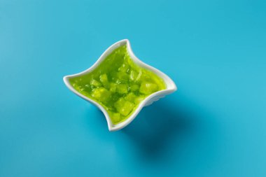 Bir kasede salatalık reçeli, mavi arka planda.