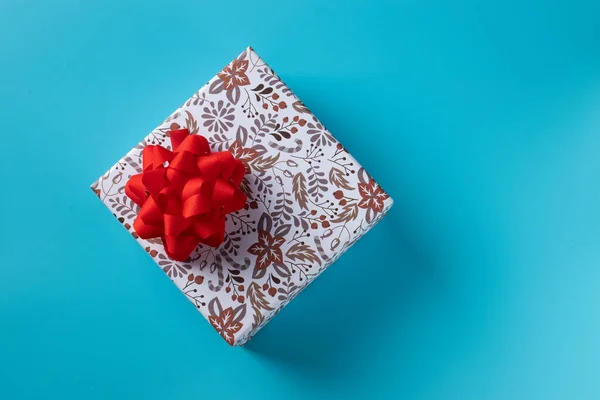 Bayram için mavi arka planda kırmızı kurdeleli hediye kutusu. Boşluğu kopyala — Stok fotoğraf
