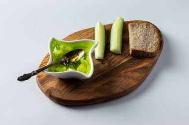 Bir kasede salatalık reçeli, ahşap bir tahtada ve beyaz arka planda