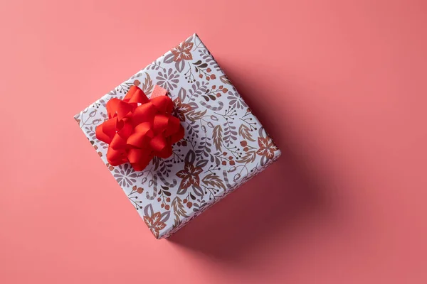 Bayram için pembe arka planda kırmızı kurdeleli hediye kutusu. Boşluğu kopyala — Stok fotoğraf