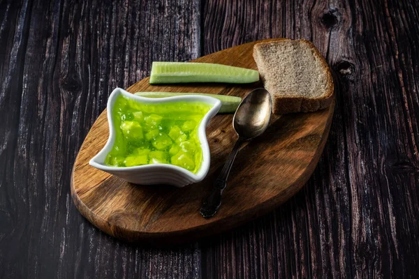 stock image Cucumber jam in a bowl on a wooden background with a slice of bread