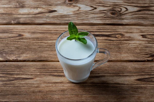 Айран в стакане, забродивший напиток, кислое молоко, украшенное листком мяты — стоковое фото
