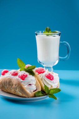 Kefir bir nane yaprağı, mayalanmış bir içecekle süslenir. Bir fincan tabağında hava keki.